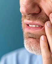 Man experiencing some soreness after dental implant surgery