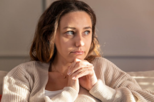 Woman sitting with her hands clasped together in concern